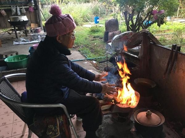 A man keeps himself warm by an open fire in northern Thailand.