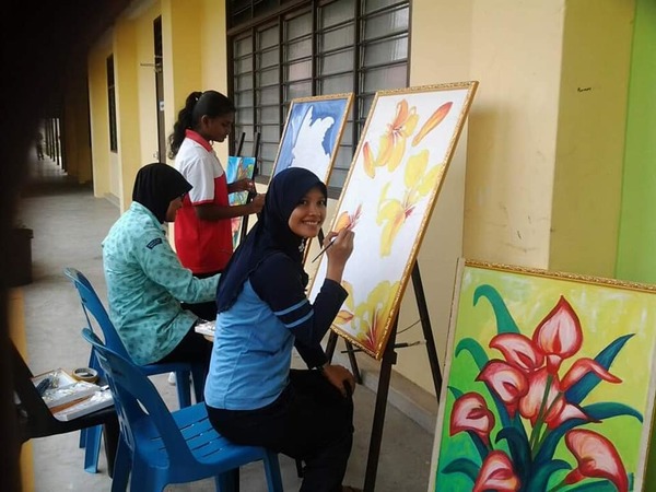 Cikgu Jue teaching students how to paint on easels