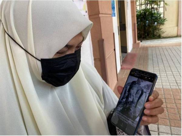 The grandmother holding her mobile with a photo of the victim.