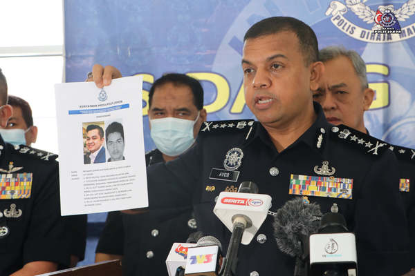 Johor police chief Datuk Ayob Khan Mydin Pitchay holding up a wanted notice of Md Azar Izwan.