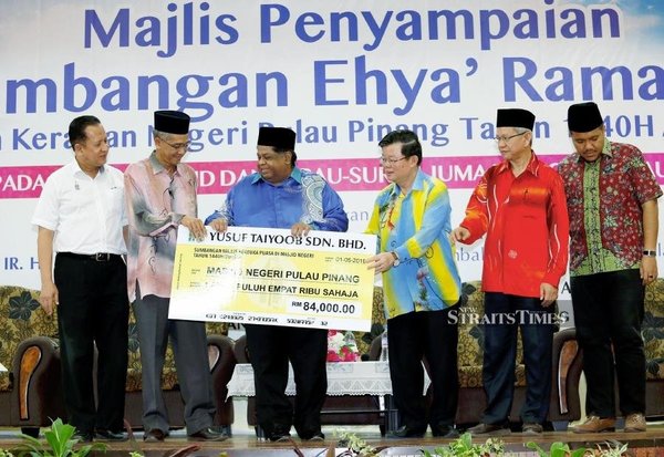 Yusuf presenting RM84,000 in cash and 200 cartons of dates to be distributed to mosques and suraus in Penang in 2019.