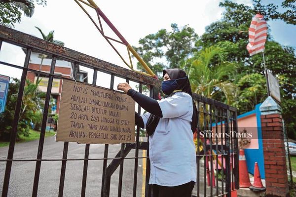 A staff member putting up a closure sign on SMK USJ 23's gate in Subang Jaya on Tuesday, 20 April.