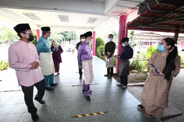 The Ministry of Higher Education DG in the middle, wearing a lavender-coloured Baju Melayu.