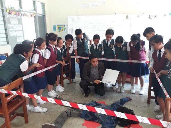 Cikgu Nazmi reenacting a crime scene in the classroom.