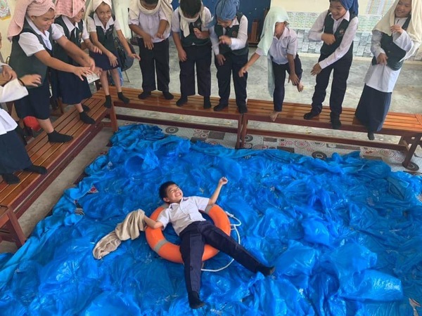 With towels wrapped around their heads, students learn what to do at swimming pools.