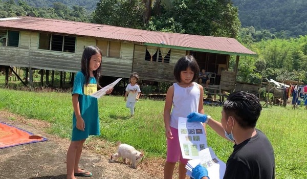 Cikgu Nazmi handing out homework and school materials to students in remote villages.