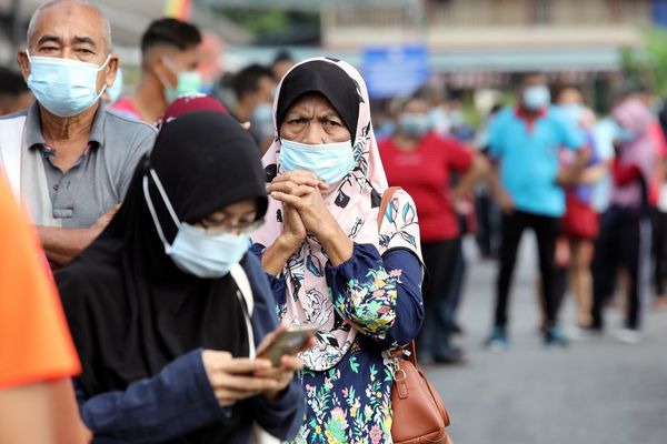 People wait in line to be tested for COVID-19 at a testing station in Klang.