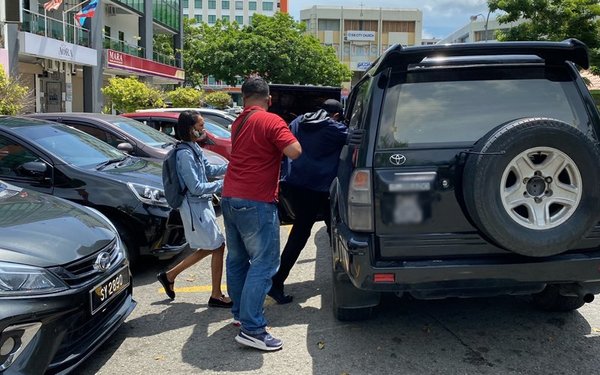 Phillip Among (in blue jacket) being taken into the unmarked police vehicle.