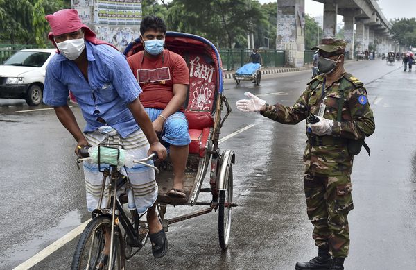 An army personnel gestures to a rickshaw driver at a road checkpoint in Dhaka.