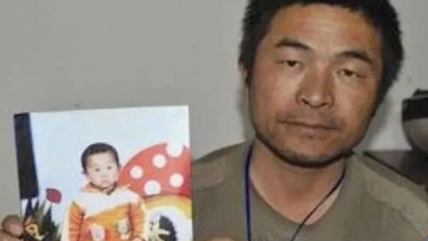 The boy's father, Guo Gangtang, holds a photograph of his kidnapped son, Guo Xinzhen.