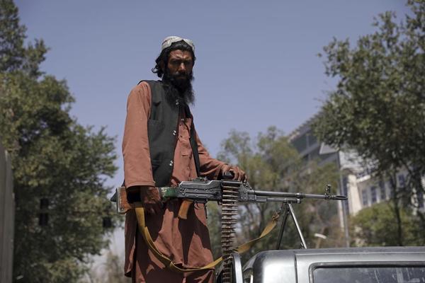 A Taliban fighter stands guard at the main gate leading to the Afghan presidential palace in Kabul on 16 August.