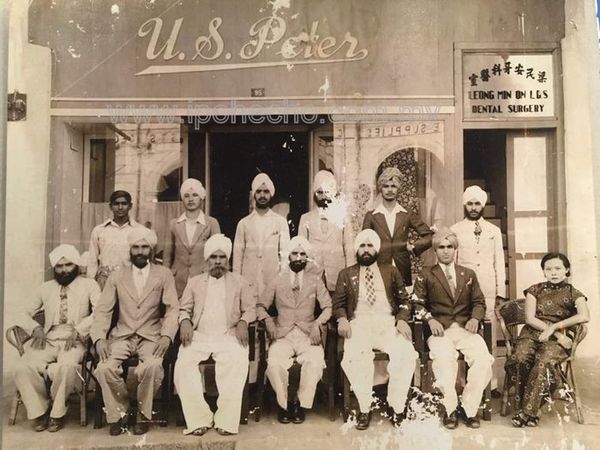 The 12 tailors of U.S. Peter in front their shop at 95, Belfield Street, with Pertap (front row, centre) and Missy (front row, right).