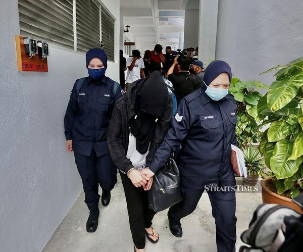 Policewomen escort Ieda Nor (centre) at the Bangi Magistrate’s Court ahead of the trial.