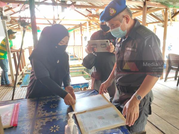 Norasyikin shows the food menu and prices to KPDNHEP officers.