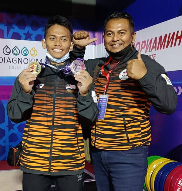 Aniq Kasdan (left) holding up his Commonwealth Championships gold medal and World Championships silver in Tashkent on Tuesday, 7 December.