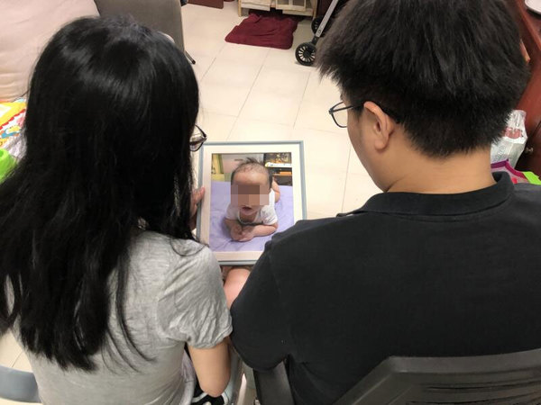 Father Yong Zhen Cheng (right) and mother Du Jing Lei looking at a photo of their baby, Yong Jing Yu.