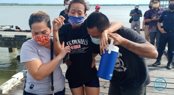 Dynasty Chang (centre) being helped by her husband and a relative as they left the Muara Tebas Wharf.