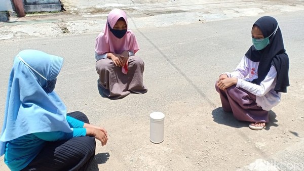 The girls' shadows are falling directly beneath them, but the bottle is not casting any shadow at all.